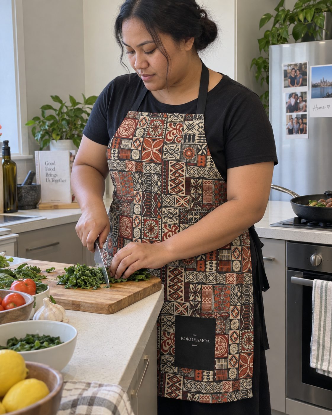 Apron in the Elei Print print, worn while cooking at a home kitchen bench.